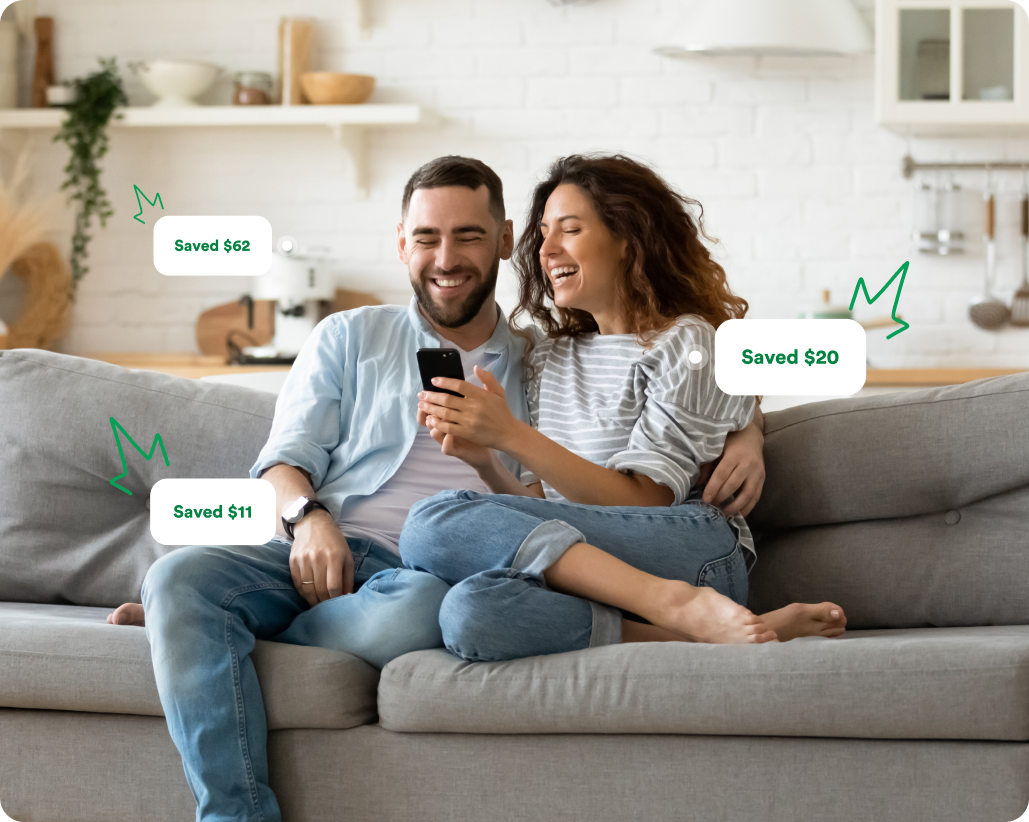 couple sitting on couch happily looking at savings on the Capital One Shopping App